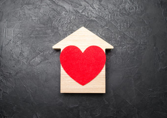 Red Heart inside a wooden house on a gray concrete background. The concept of a love nest, the...