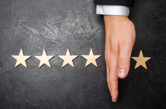 The hand of the businessman separates the fifth star from the other four. The loss of the fifth star, the fall in rating and recognition. The critic takes the fifth star from the hotel, restaurant.