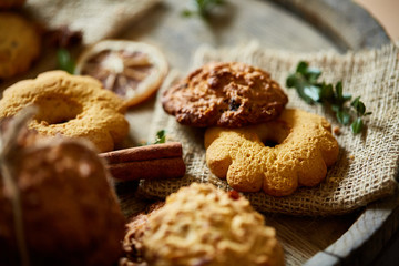 Conceptual composition with assortment of cookies and cinnamon on a wooden barrel, selective focus, close-up