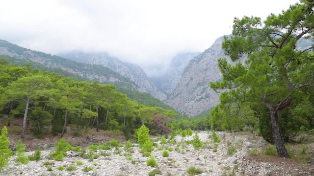 Beautiful cloudy scenic landscape. Dry stony bottom of river in forest. Camera moving from right to left. Taurus mountains in Turkey, Beldibi, between Kemer and Antalya turkish cities in distance.