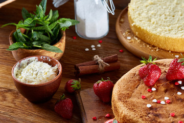 Baking background with strawberry tart covered with whipped sour cream, ingredients over wooden background.