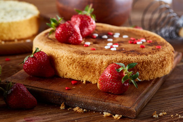 Delicious cake with fresh organic strawberries and kitchen utensils, top view, close-up, selctive focus.