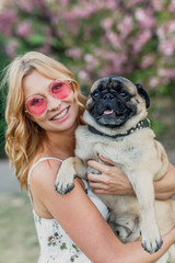 portrait of a beautiful young girl in a white dress and pink glasses with a dog