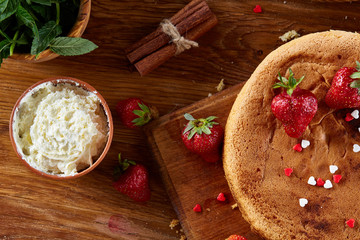 Baking background with strawberry tart covered with whipped sour cream, ingredients over wooden background.