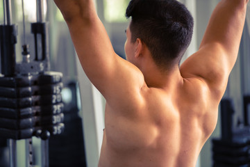 Portrait of young man using weight lifting equipment to build a massive chest and arm at indoor sport gym , bodybuilder concept.