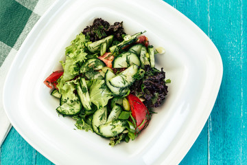vegetable salad on a blue wooden background, cucumber, tomato