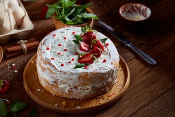 Strawberry tart covered with whipped sour cream on a wooden tray over rustic background, selective focus