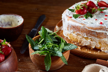 Strawberry tart covered with whipped sour cream on a wooden tray over rustic background, selective focus