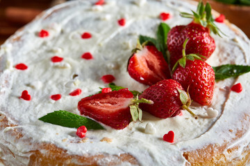Strawberry tart covered with whipped sour cream on a wooden tray over rustic background, selective focus