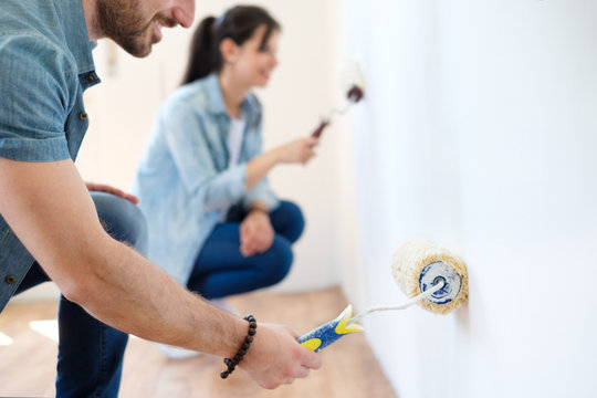 Portrait Of Smiling Young Couple Painting Interior Wall Of New Apartment