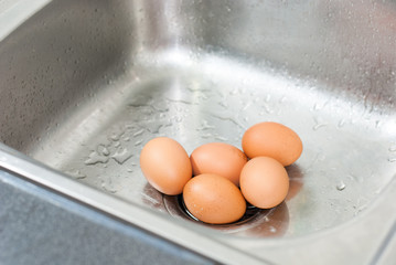 Five big brown eggs lay on metal sink in kitchen for washing and cooking so on, quality ingredient