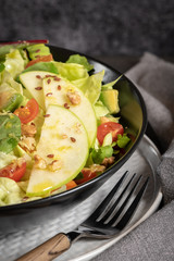 Salad. Spring vegetable salad. Fresh vegetable salad with tomatoes, apple, nuts, seeds and lemon. Olive oil pouring into bowl of salad.