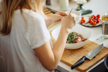 Home cozy kitchen chef pours salt on pork or beef meat with salt shaker Barbecue concept or healthy...