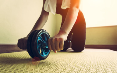 Attractive woman with abdominal exercises with wheel. Workout at home to lose weight indoor room