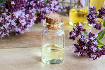 Obraz na płótnie Canvas A bottle of essential oil with fresh blooming oregano