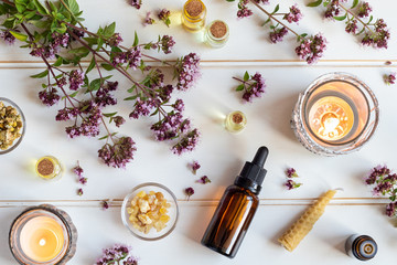 Bottles of essential oil with blooming oregano, frankincense and other herbs