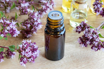 A bottle of oregano essential oil with blooming oregano twigs
