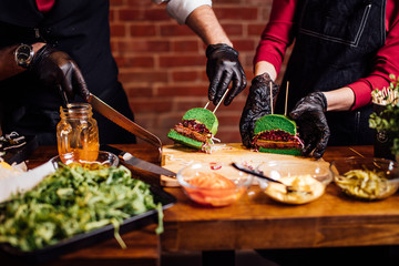 Masterclass in Burger pub. Chef cutting burger into two halfs to perform quality ingredients
