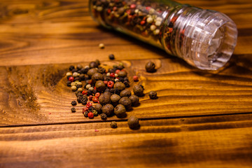Pepper mill and scattered spices on the wooden table