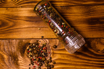 Pepper mill and scattered spices on the wooden table. Top view