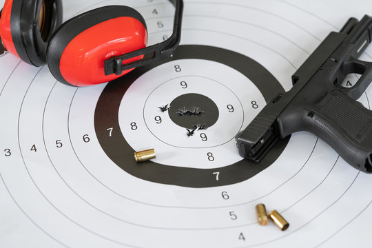 Close up shot of a shooting target and bullseye with bullet holes with automatic pistol gun and cartridge bullet.