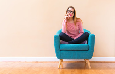 Happy young woman in a big chair smiling in a big open room