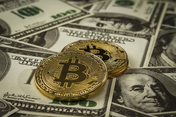 Coin in the form of bitcoin on a pile of dollar bills