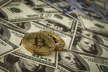 Coin in the form of bitcoin on a pile of dollar bills