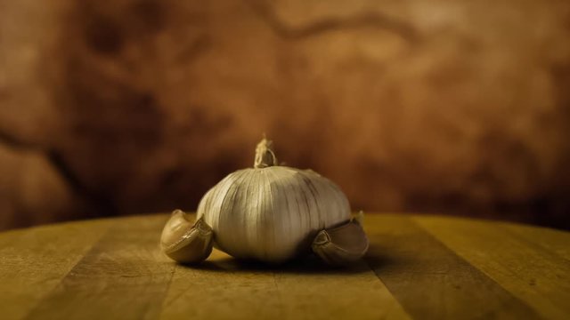 Head of garlic and cloves of garlic on wooden desk. Rotating, turntable shot. Still life
