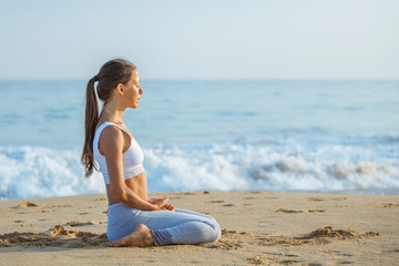 Fototapeta na wymiar Caucasian woman practicing yoga at seashore of tropic ocean