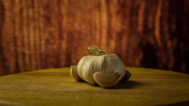 Head of garlic and cloves of garlic on wooden desk. Rotating, turntable shot. Still life
