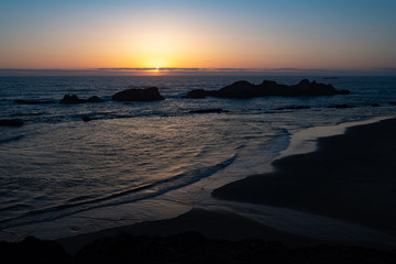 Sunset over pacific ocean with rocks in the water. Yachts, Oregon