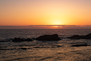 Fototapeta na wymiar Sunset over pacific ocean with rocks in the water. Yachts, Oregon