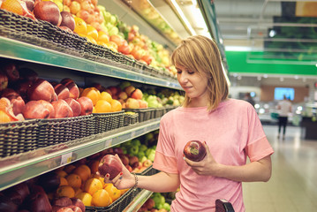 Girl choosing apples during shopping at supermarket.