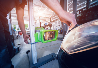 Worker checks and adjusts the headlights of a car's lighting system © romaset