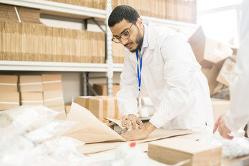 Measuring equipment factory worker wearing lab coat wrapping manometer in paper while preparing...