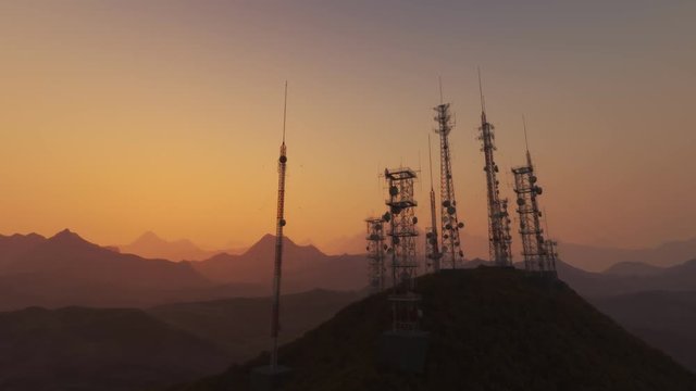 Antenna complex on a hill flythrough. Tall masts or towers during sunset.