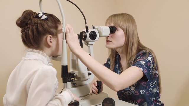 Professional ophtgalmologist using slit lamp at the office for biomicroscopy of the eyes. Working with a child.