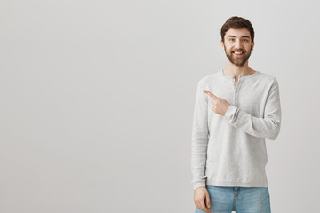Look at my partner in crime. Portrait of good-looking emotive young male pointing left with index...
