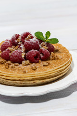 traditional thin pancakes with fresh raspberries on wooden table, vertical
