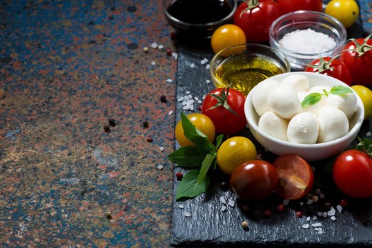 mozzarella, fresh vegetables and spices and dark background for text, horizontal