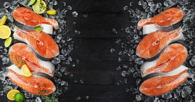 Fresh salmon steaks on ice, on black background. Top view. Copy space
