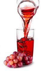 Grape juice pouring from jug into transparent glass
