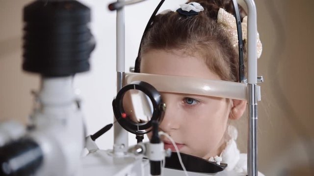 Close up shot of a girl sitting on eye biomicroscopy. She is getting her eye examined on a slit lamp.