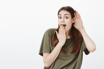 Studio shot of positive good-looking woman with brown hair, tilting right while overhearing...