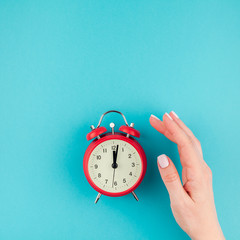 Woman hand holding the red vintage alarm clock