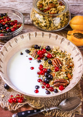 Bowl of homemade granola with yogurt and fresh berries on wooden background from top view