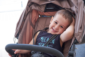 cheerful baby sitting in a wheelchair and smiling