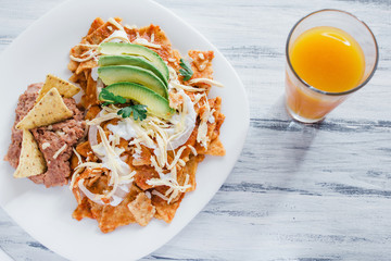 Chilaquiles rojos with chicken, avocado and juice, mexican food, breakfast in mexico city