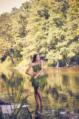 Summer heat. Beautiful young girl in a forest lake, open clothes from fern leaves, perfectly combined with nature. A person in the form of a fantasy elf, dryads, cosplay of a character.
